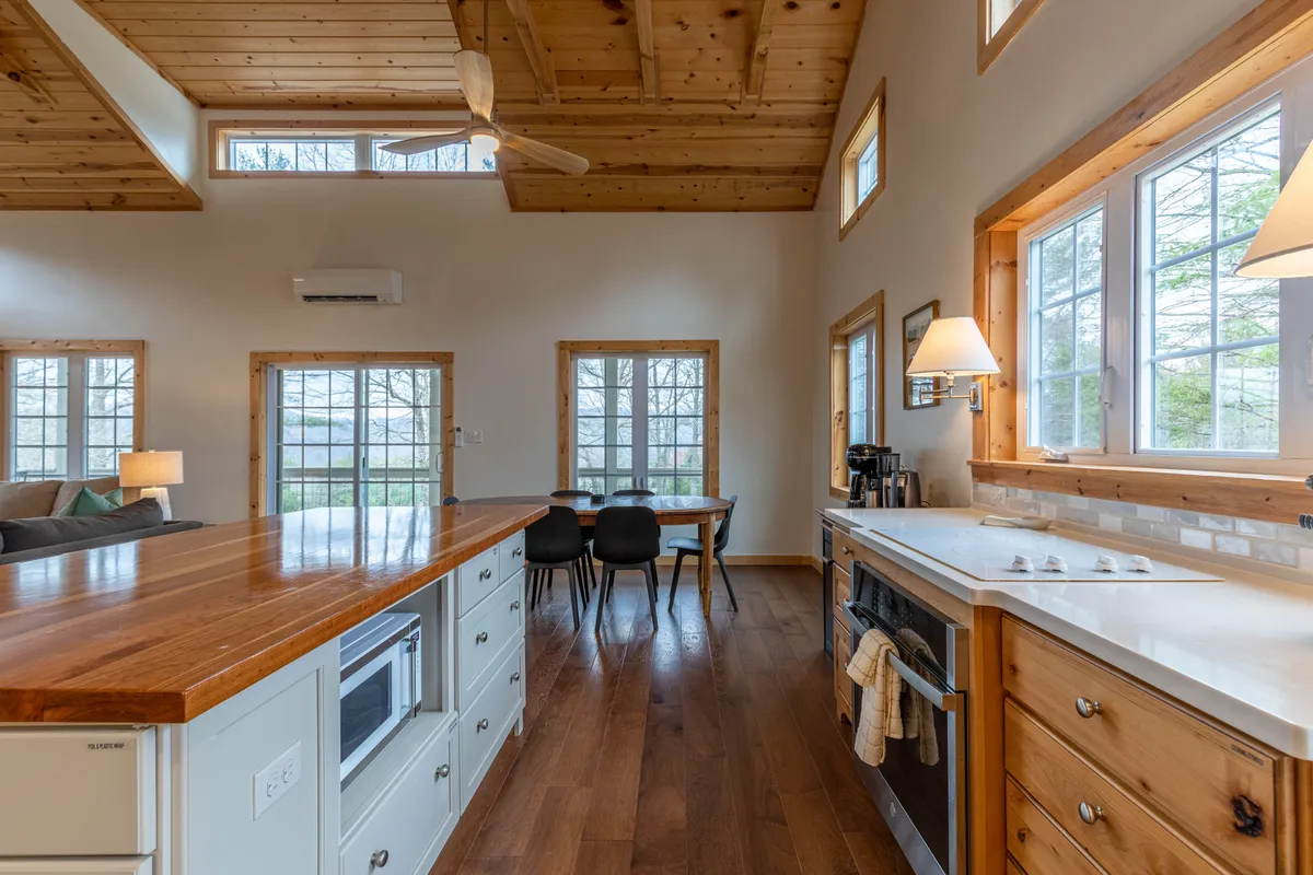This angle provides a broader look at the kitchen’s open layout, featuring the kitchen island, large windows, and an adjoining dining area. The scene suggests a relaxed setting for making breakfast or hosting friends, with an atmosphere that blends practicality and warmth.