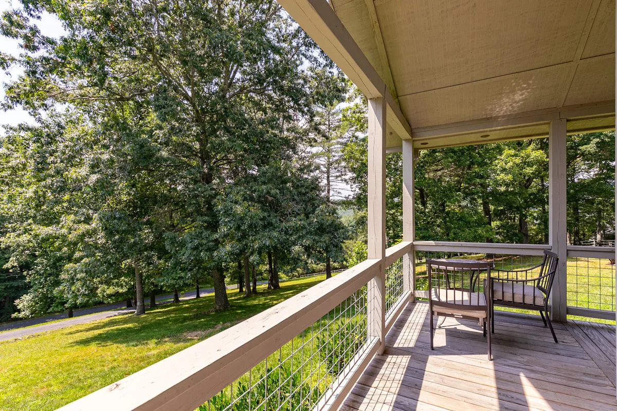 An inviting wooden deck with comfortable outdoor seating overlooks lush greenery, creating a tranquil space for morning coffee, relaxing with a book, or enjoying the evening air under the stars.