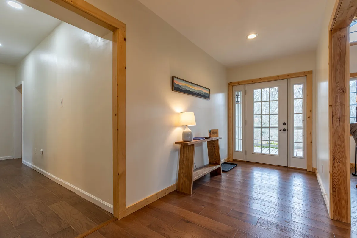 A view of the inviting front entrance, highlighting a warmly lit foyer with a console table, lamp, and tasteful wall art. The door hints at the transition point between the comfort of the home and the excitement of the outdoors.