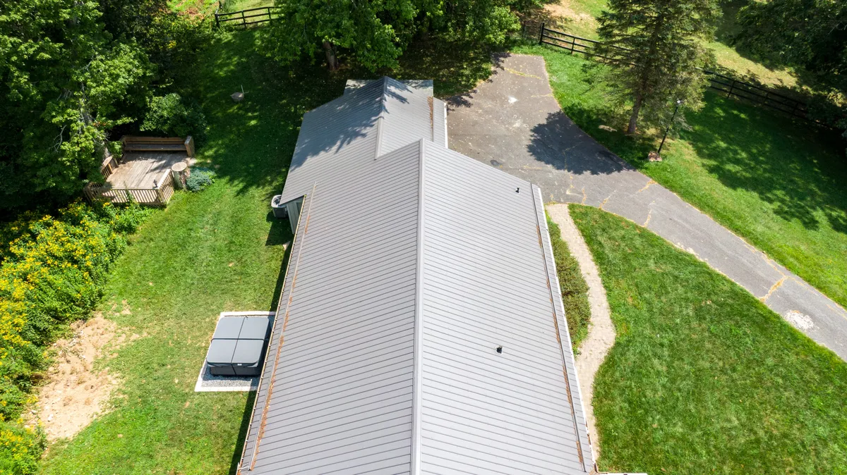 A tranquil exterior shot featuring the property's distinctive roof design, a well-landscaped garden, a welcoming driveway, and an inviting outdoor seating area. The scene is bathed in natural light, evoking the allure of spending time outdoors in every season.
